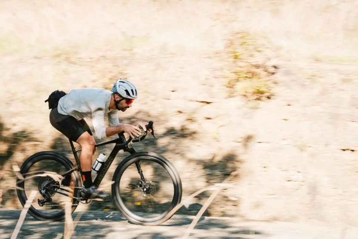 Person in sportlichen Klamotten auf Cannondale Gravelbike umgeben von hellem, kahlen Untergrund