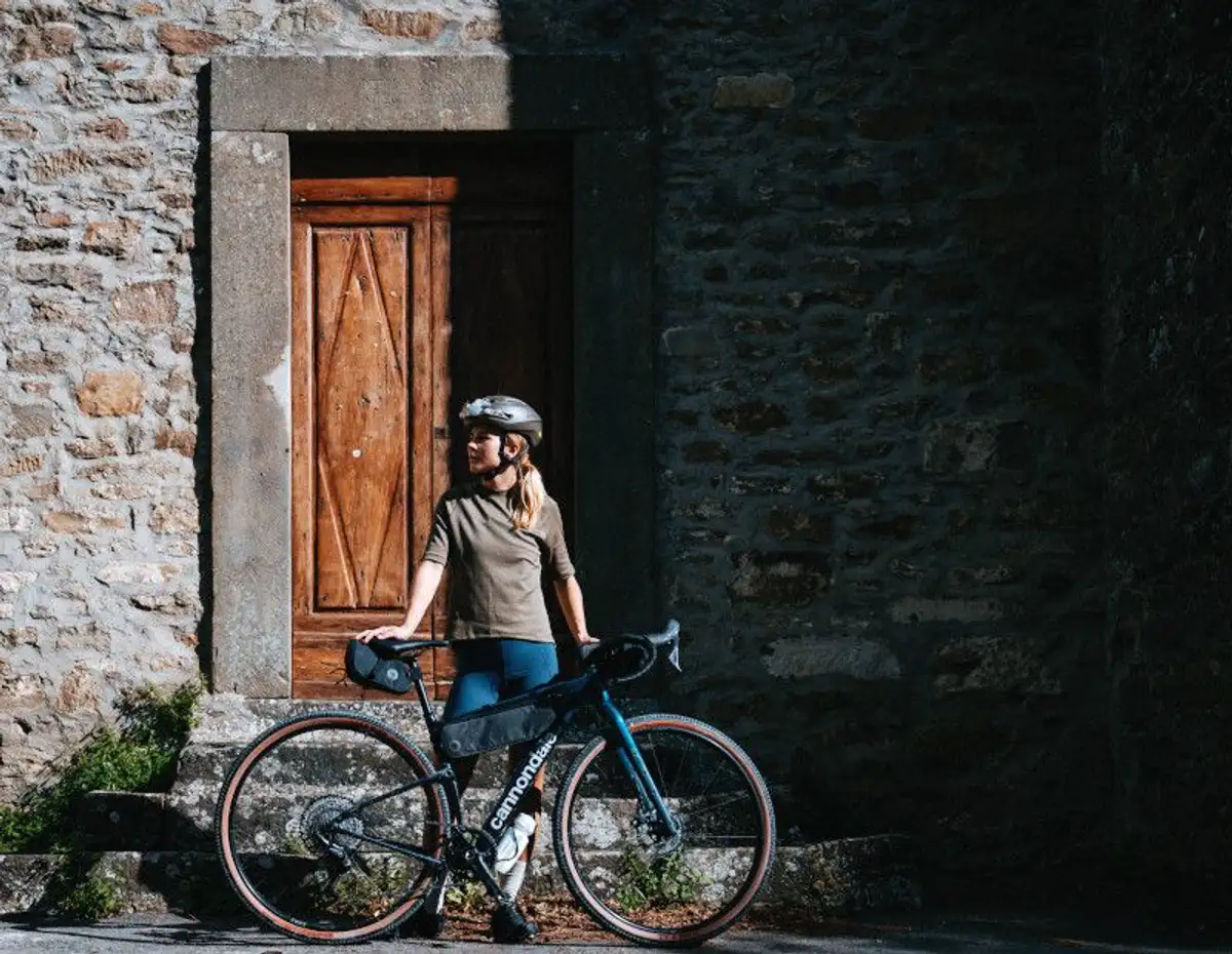 Frau steht vor Hauswand hinter Cannondale Fahrrad und schaut nach links