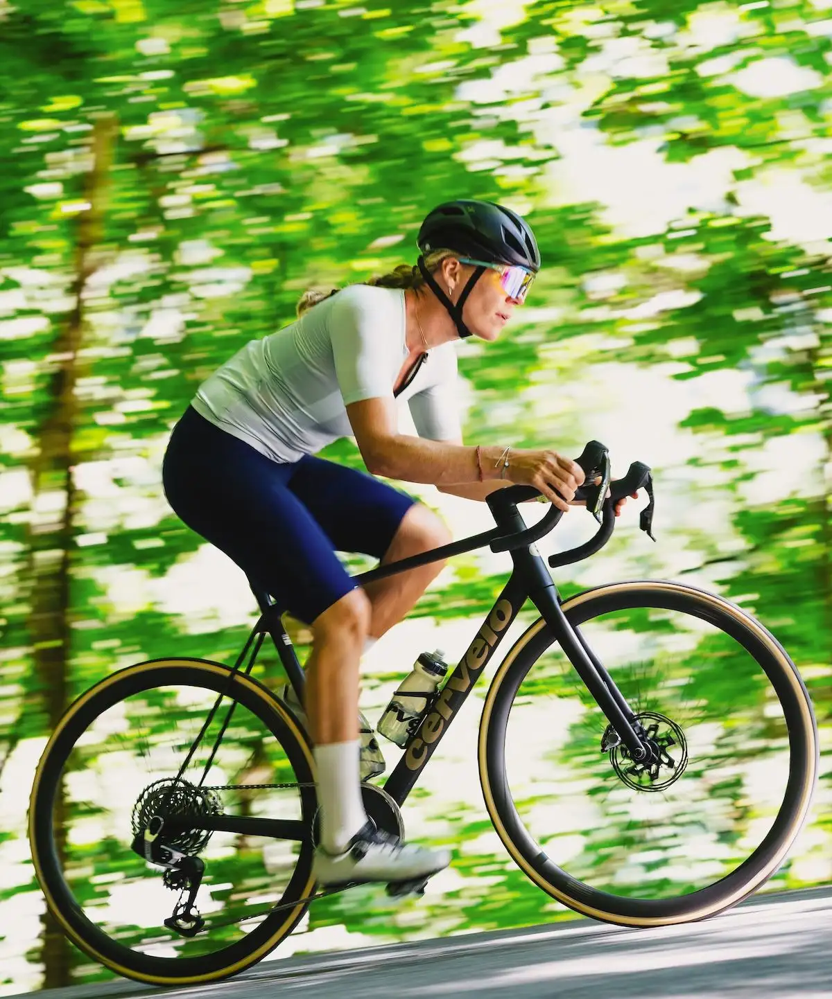 Fahrerin in sportlichen Klamotten auf Cervelo Rad vor grünem, verschwommenem Hintergrund