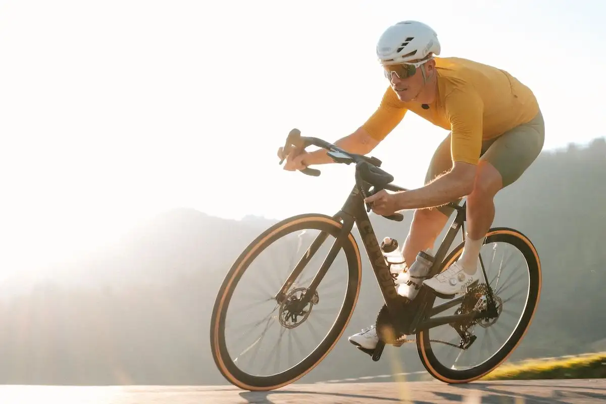 Mann in sportlichen Klamotten auf Cervelo Rennrad vor hellem, sonnigem Hintergrund
