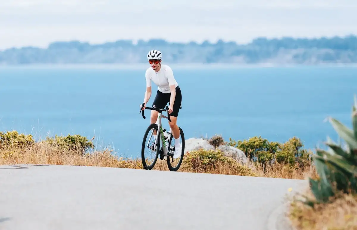 person on race bike riding uphill in front of ocean