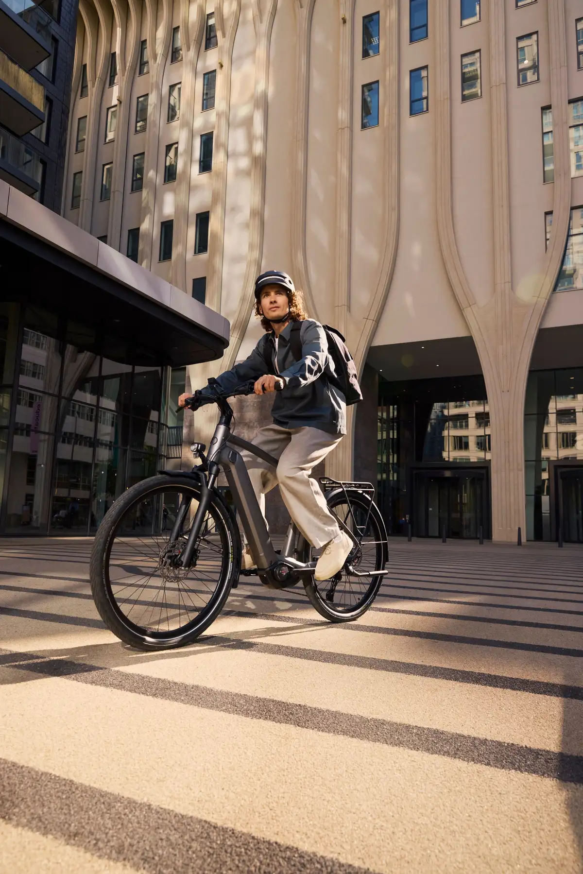 Junger Mann fährt mit E-Bike durch städtische Umgebung