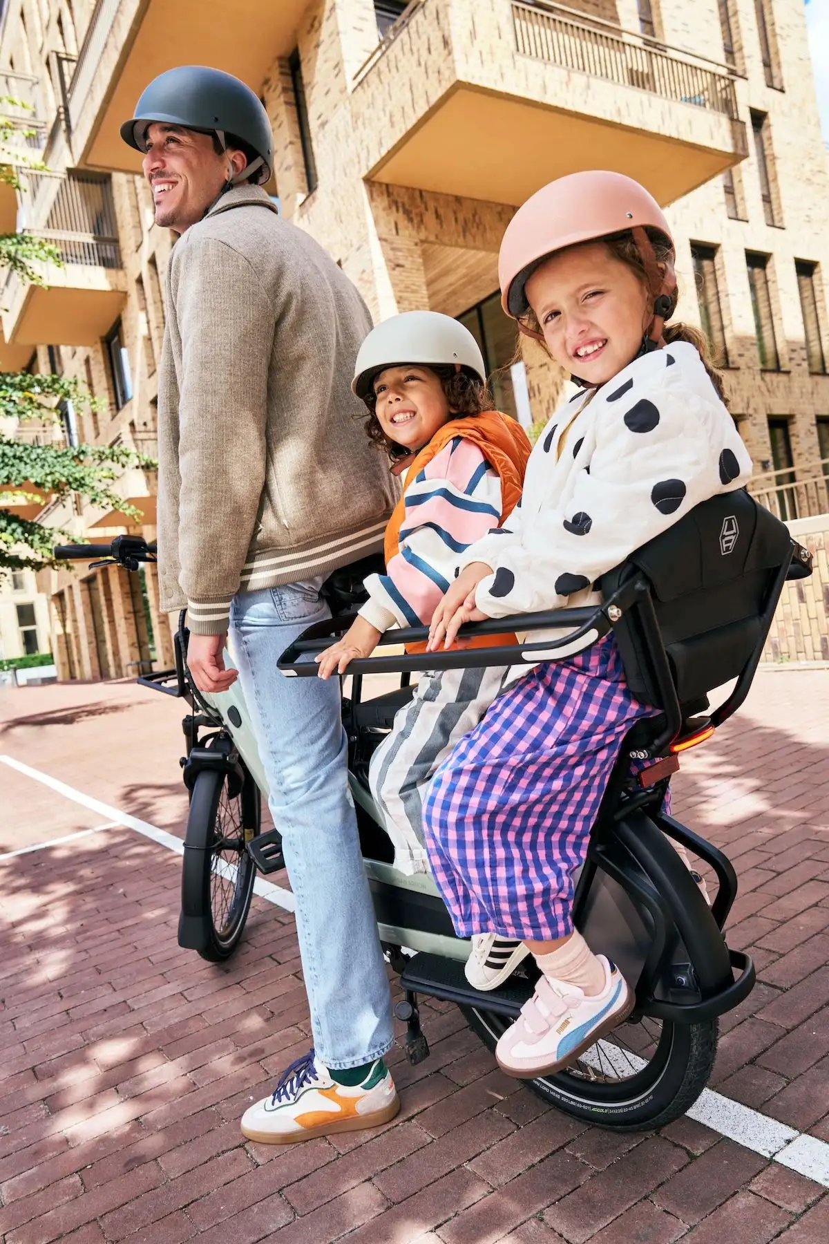 two kids sitting in the back of urban arrow bike with man in front