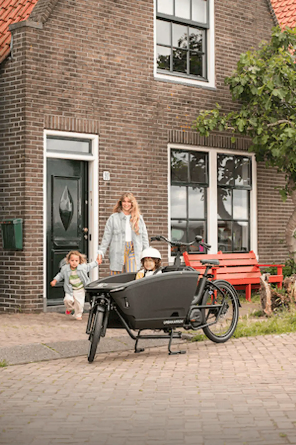 Frau geht mit Kindern auf Lastenrad zu