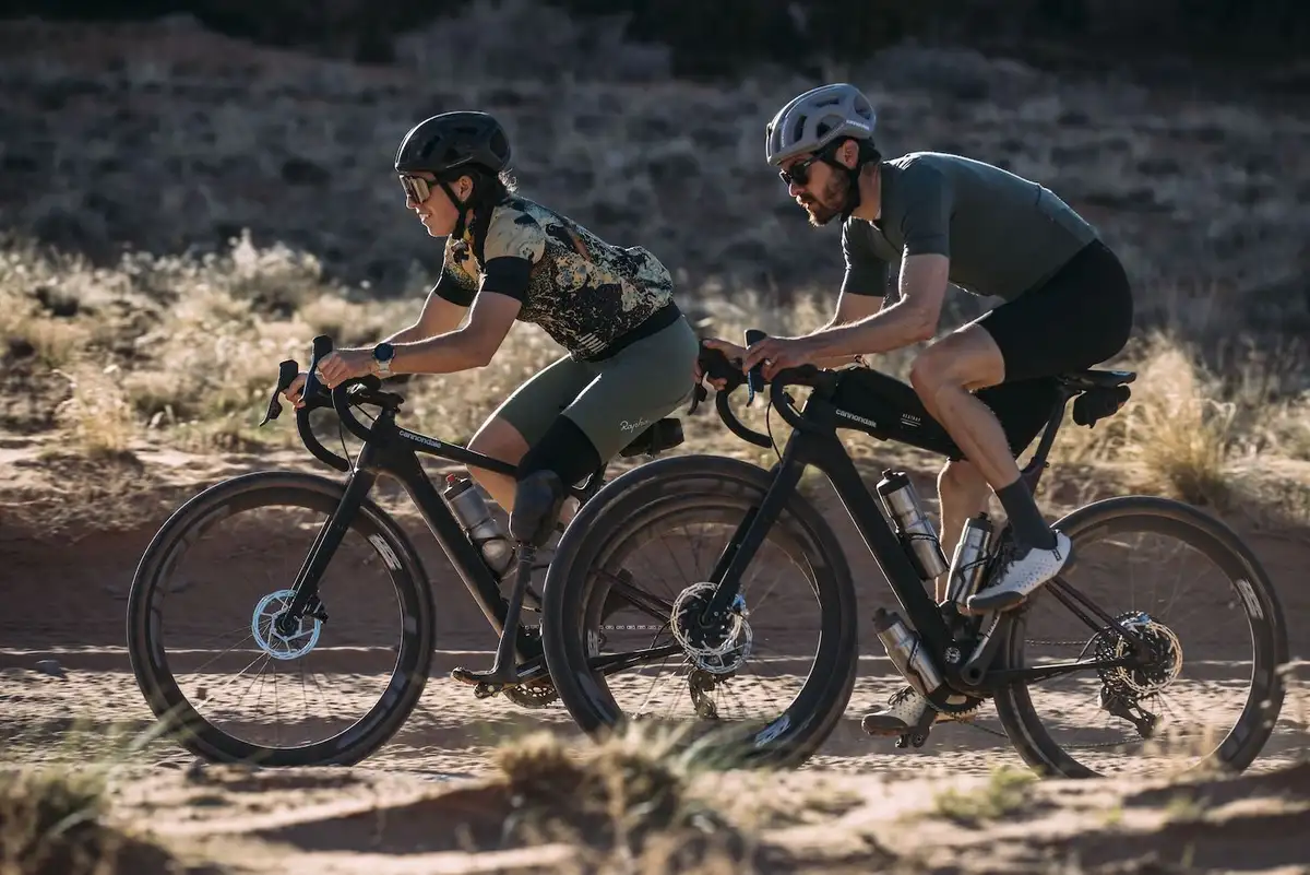 Frau und Mann auf Cannondale Gravelbikes auf sandigem Boden