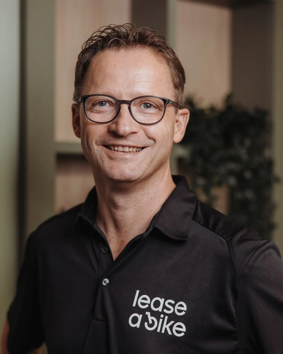 Portrait of Christian Wölbern, Managing Director of Lease a Bike, wearing a branded polo shirt.