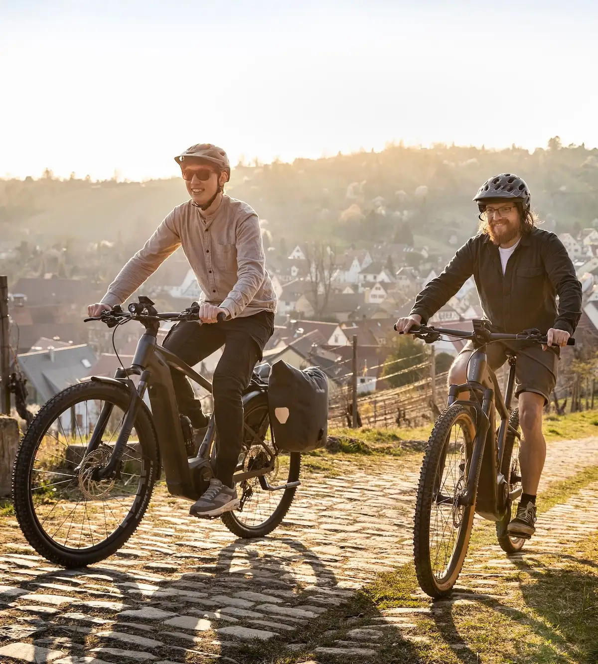 Zwei Radfahrer auf E-Bike fahren bergauf in sonnigem Wetter