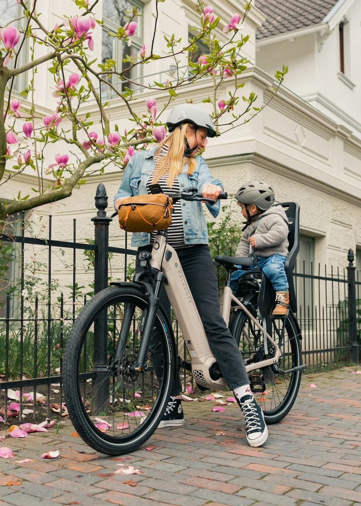 young woman is riding job bike with kid in the back