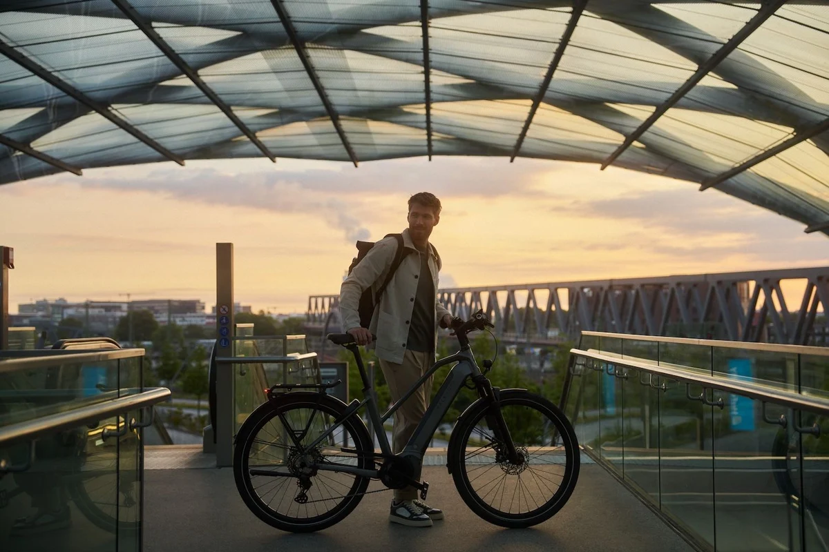 Mann mit Fahrrad steht vor Sonnenuntergang und Skyline