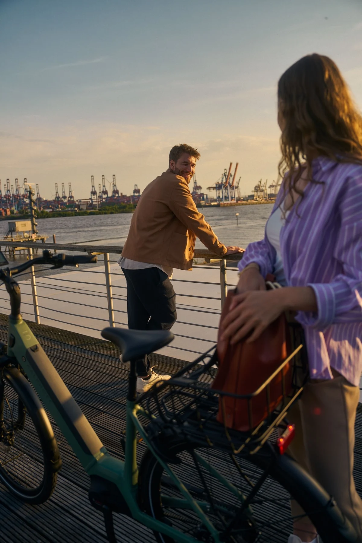 Mann und Frau schauen sich an und stehen mit Kalkhoff Fahrrad am Hafen