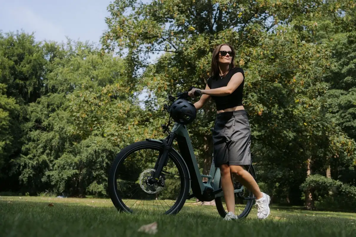 Frau schiebt Kalkhoff Fahrrad durch Park