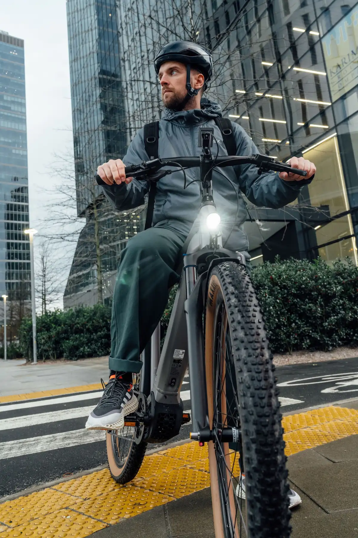 Mann mit Kalkhoff E-Bike steht vor Bürogebäude Licht an und schaut nach links