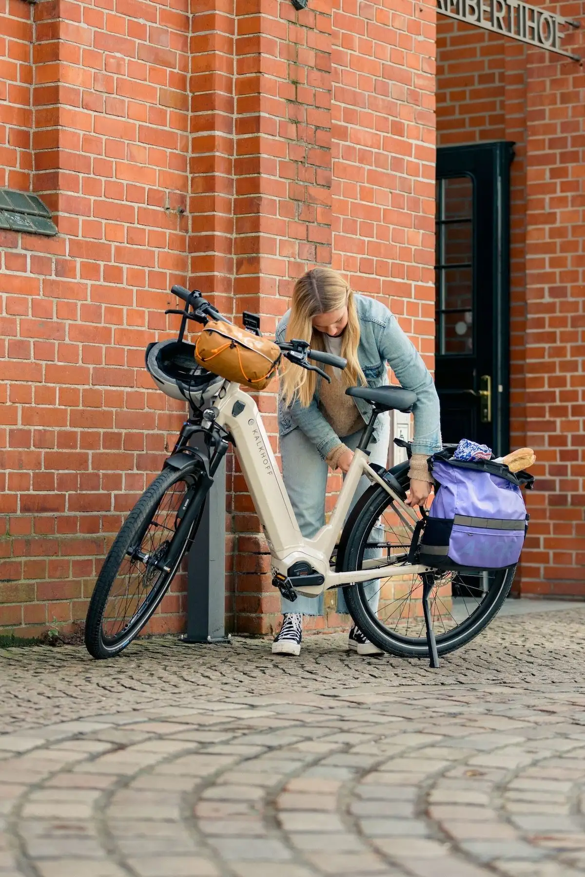 Young woman locks Kalkhoff e-bike in front of building