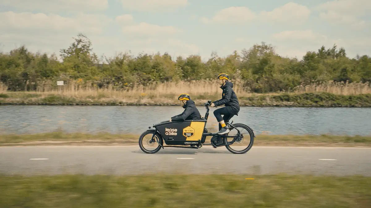 Frau und Mann mit TVL Lastenrad auf Radweg neben Fluss