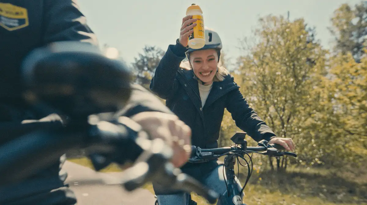 Frau auf Fahrrad mit Trinkflasche in der Hand