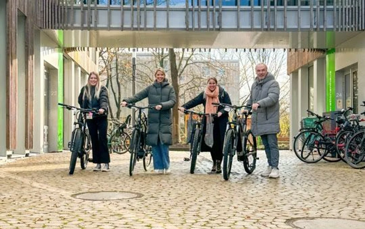 Vier Personen mit Fahrrändern vor Gebäude