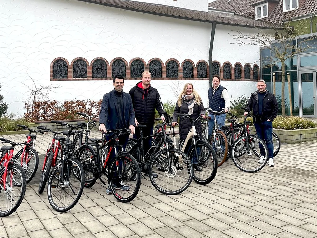 Gruppe von Menschen mit Fahrrädern vor Gebäude