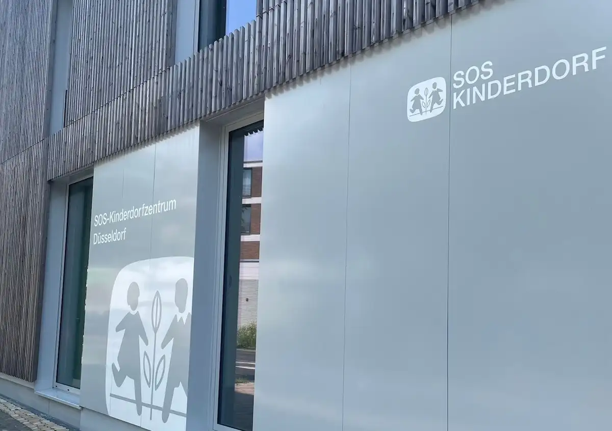 Façade of the SOS Children’s Village Center Düsseldorf with logo and window decals.