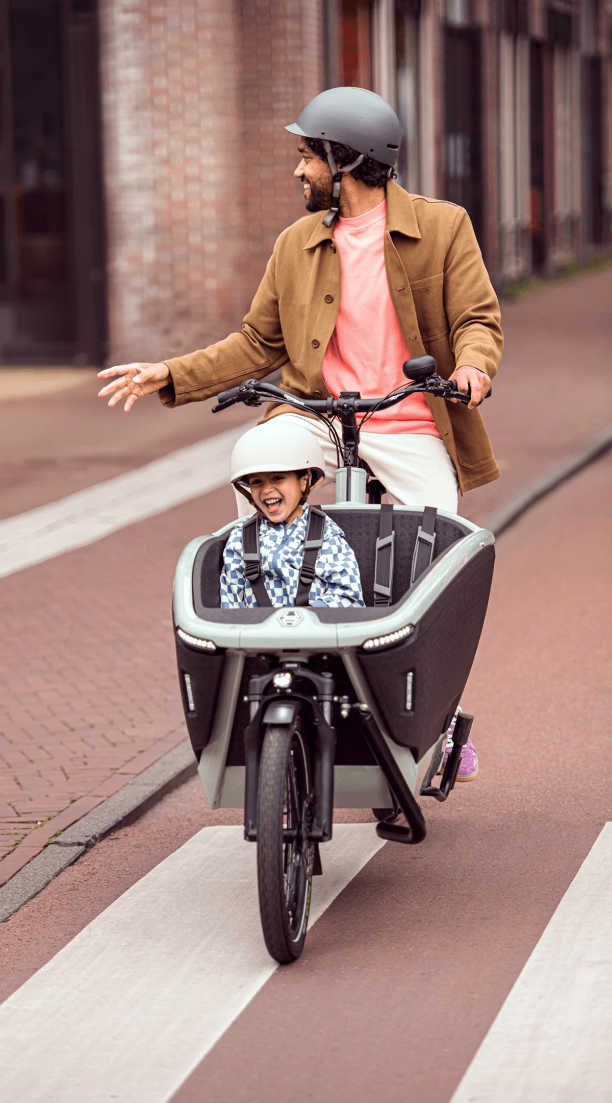 Man on a cargo bike with a child sitting in front, laughing
